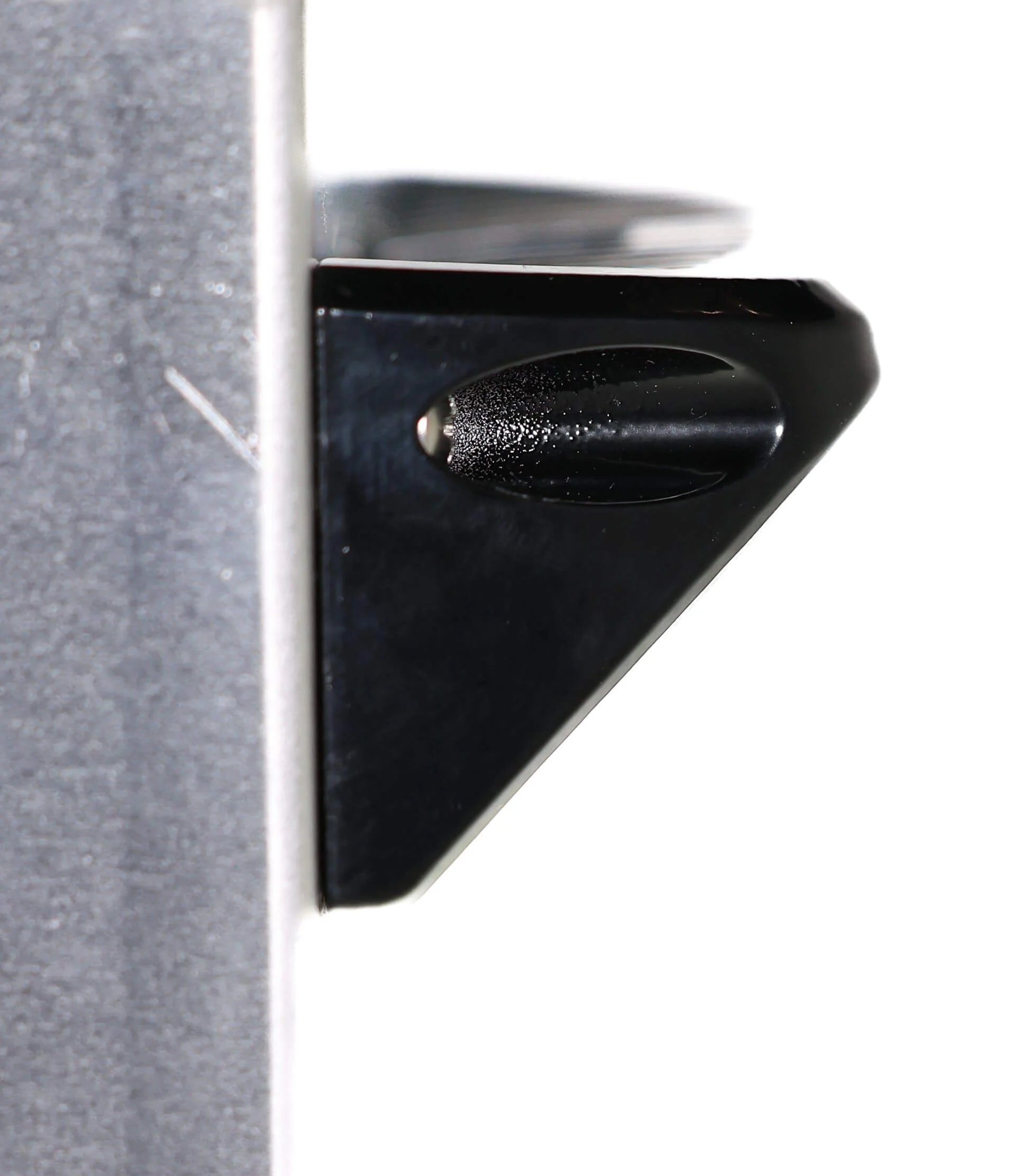 Black triangular metal bracket with textured knob attached to a vertical gray surface.